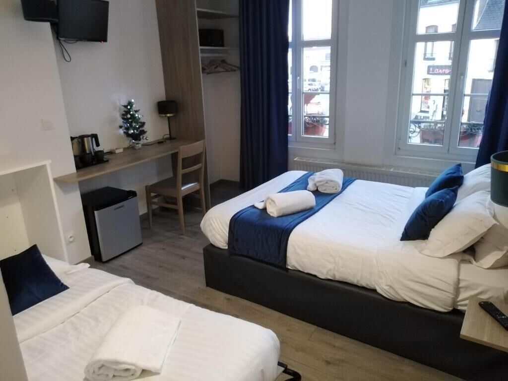 Une chambre d’hôtel avec deux lits, un bureau, un petit réfrigérateur, une télévision et une fenêtre donnant sur l’extérieur.