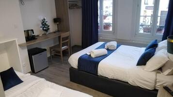 Hotelkamer met twee bedden, een bureau, een kleine koelkast, een televisie en een raam met uitzicht.