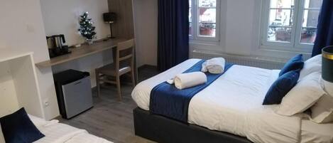 Une chambre d’hôtel avec deux lits, un bureau, un petit réfrigérateur, une télévision et une fenêtre donnant sur l’extérieur.