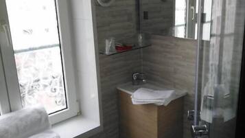 Ein modernes Badezimmer mit Duschkabine aus Glas, einem Holzbadezimmerwaschtisch und einem Fenster für natürliches Licht.