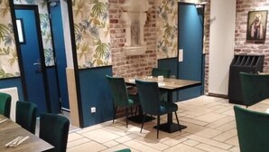 Un restaurante con paredes de ladrillo, sillas tapizadas en verde y mesas de madera.