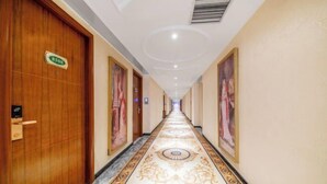Ein Hotelgang mit Holztüren, einem gemusterten Teppich und gerahmten Bildern an den Wänden.