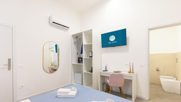 Une chambre d’hôtel comprenant un lit, un bureau, une chaise, un miroir, une armoire et une salle de bain.