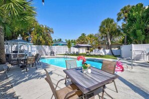 Relax by the clear pool surrounded by lush greenery and a shaded gazebo.