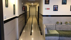 A hotel corridor with a reception area featuring a couch and wall-mounted artwork. - Wishotel Xpress 7 Eleven  (Indore)