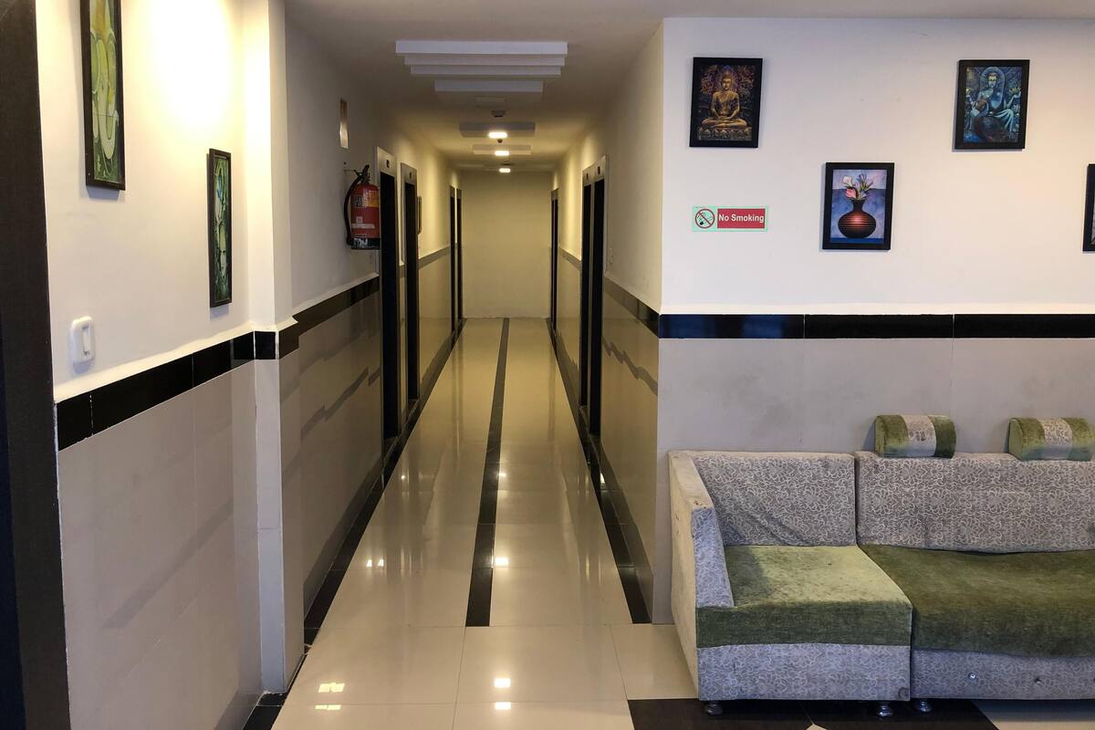 A hotel corridor with a reception area featuring a couch and wall-mounted artwork.