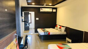 A hotel room with a bed, a desk, and a chair. There is a window and an air conditioning unit on the wall. - Wishotel Xpress 7 Eleven  (Indore)