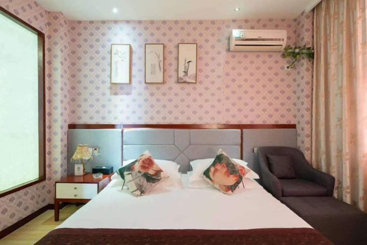 Een hotelkamer met een bed, nachtkastje, stoel en een airconditioning.