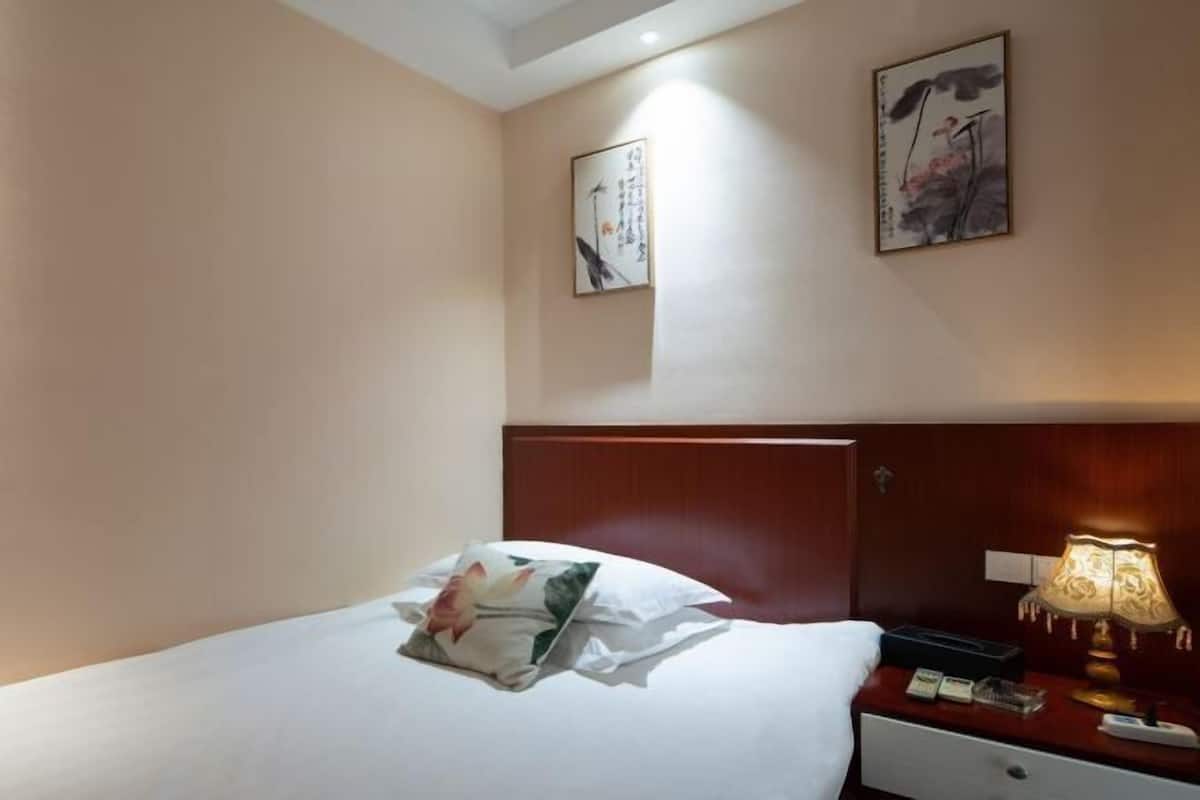 Een hotelkamer met een bed, een nachtkastje, een lamp en twee aan de muur bevestigde schilderijen.