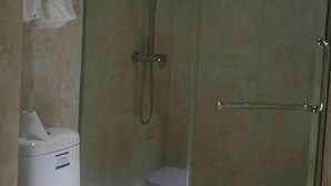 A shower enclosure with a handheld showerhead, a towel hanging on the wall, and a toilet visible through the glass door. - Kaihua Jinzhihu Hotel (Kaihua)