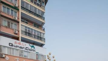 Un hotel de varios pisos con balcones y un letrero visible de 'Qunar.Com'.