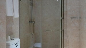 A glass-enclosed shower stall with a handheld showerhead, a toilet, and a towel rack. - Kaihua Jinzhihu Hotel (Kaihua)