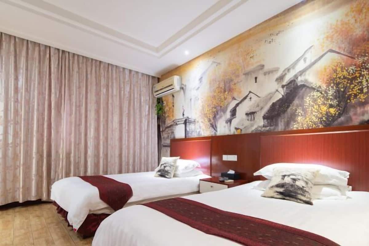 Een hotelkamer met twee bedden, een grote muurschildering en een airconditioning.