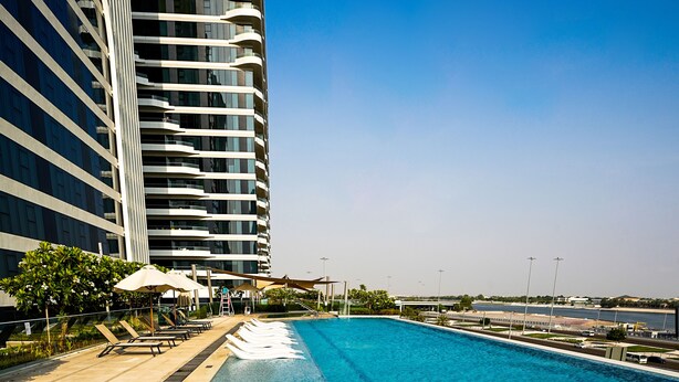 Een modern hotel met een zwembad, terras en uitzicht op zee.