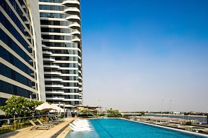 A modern hotel with a swimming pool, outdoor seating, and a view of the sea.