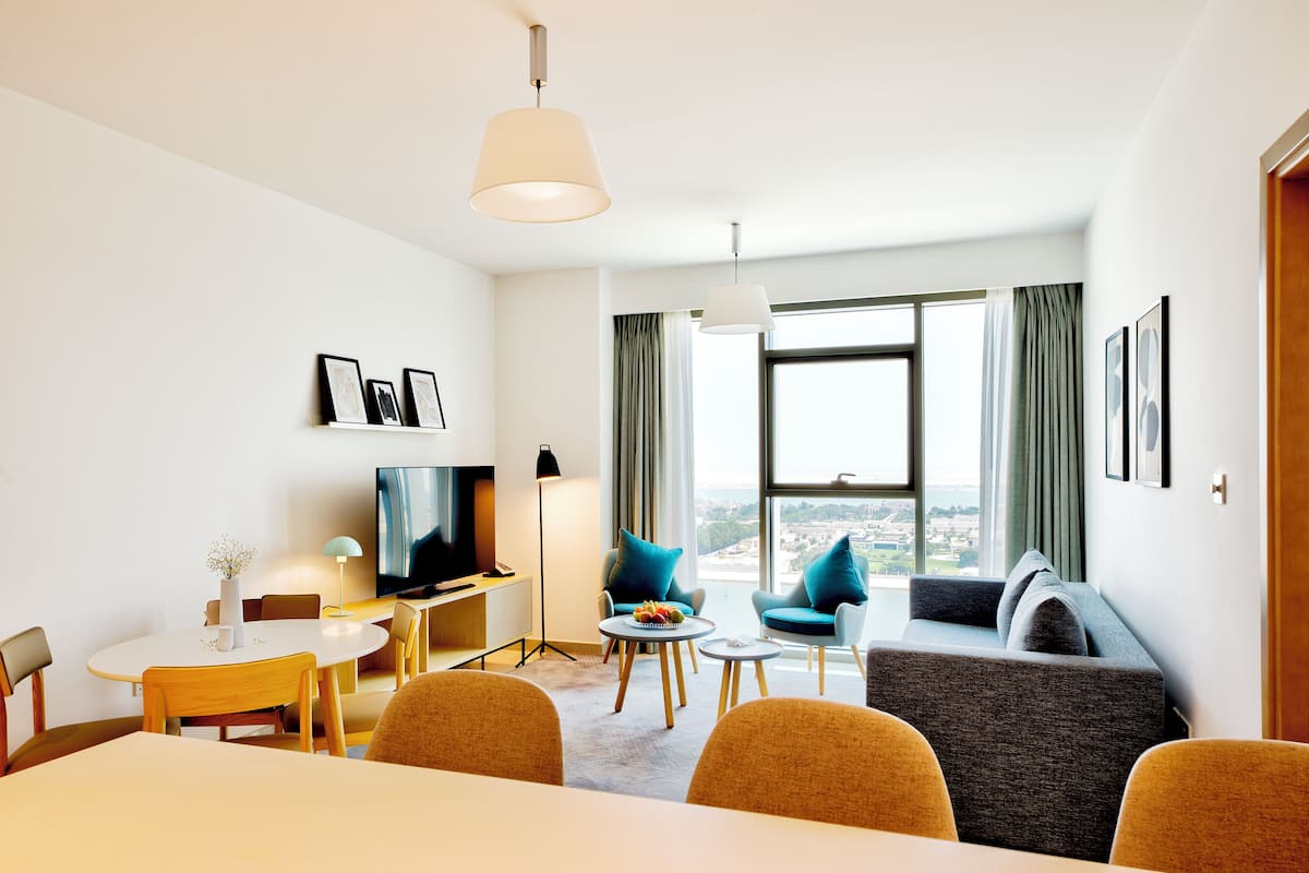 Une chambre d’hôtel moderne dotée d’un coin repas, d’un canapé et d’une télévision.