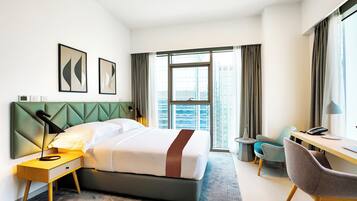 Une chambre d’hôtel moderne, dotée d’un grand lit, d’un bureau, d’une chaise et offrant une vue sur la ville.