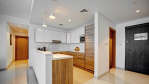 Een moderne keuken met witte kasten, een houten eiland en een donkerhouten deur.