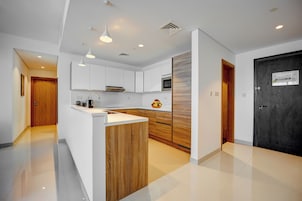 Una cocina moderna con armarios blancos, una isla de madera y una puerta de madera oscura.