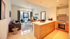 Een modern appartement met keuken, eethoek en woonkamer. Het heeft een groot raam, een bank, salontafel en een keukeneiland.