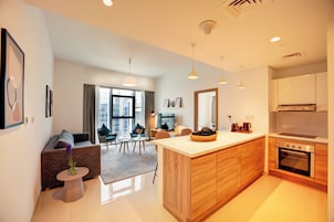 A modern apartment with a kitchen, dining area, and living room. It features a large window, a sofa, a coffee table, and a kitchen island.