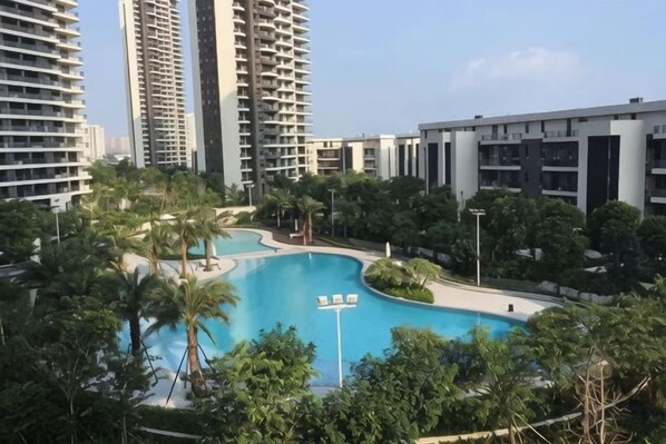 Un complejo residencial con edificios altos, piscina y zonas verdes circundantes.
