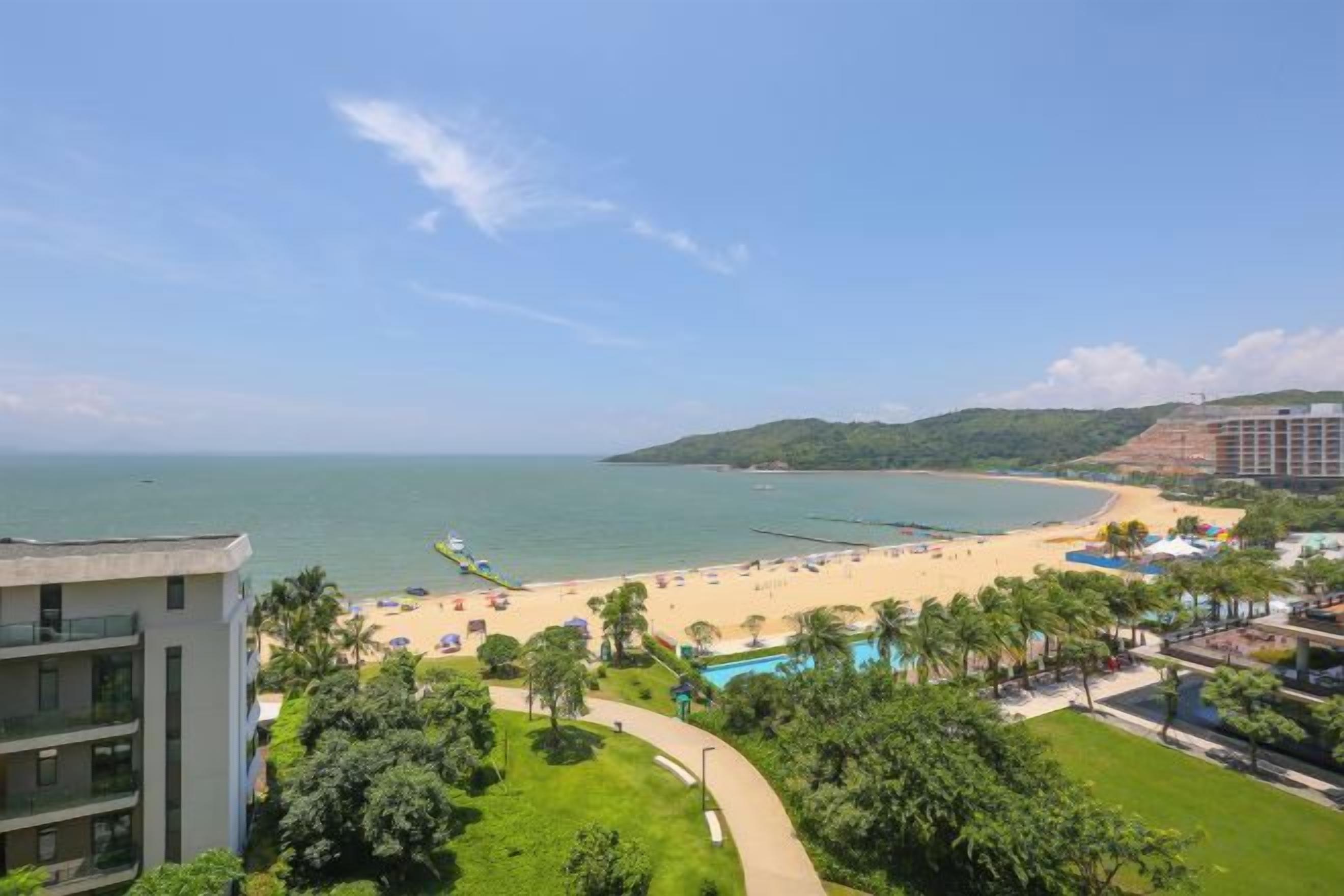 A coastal hotel with a beach view, a pool, and lush greenery.