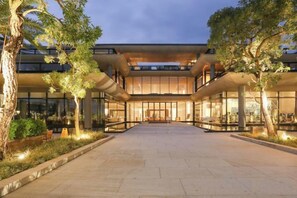 A modern building with a central courtyard, surrounded by trees and featuring large windows.