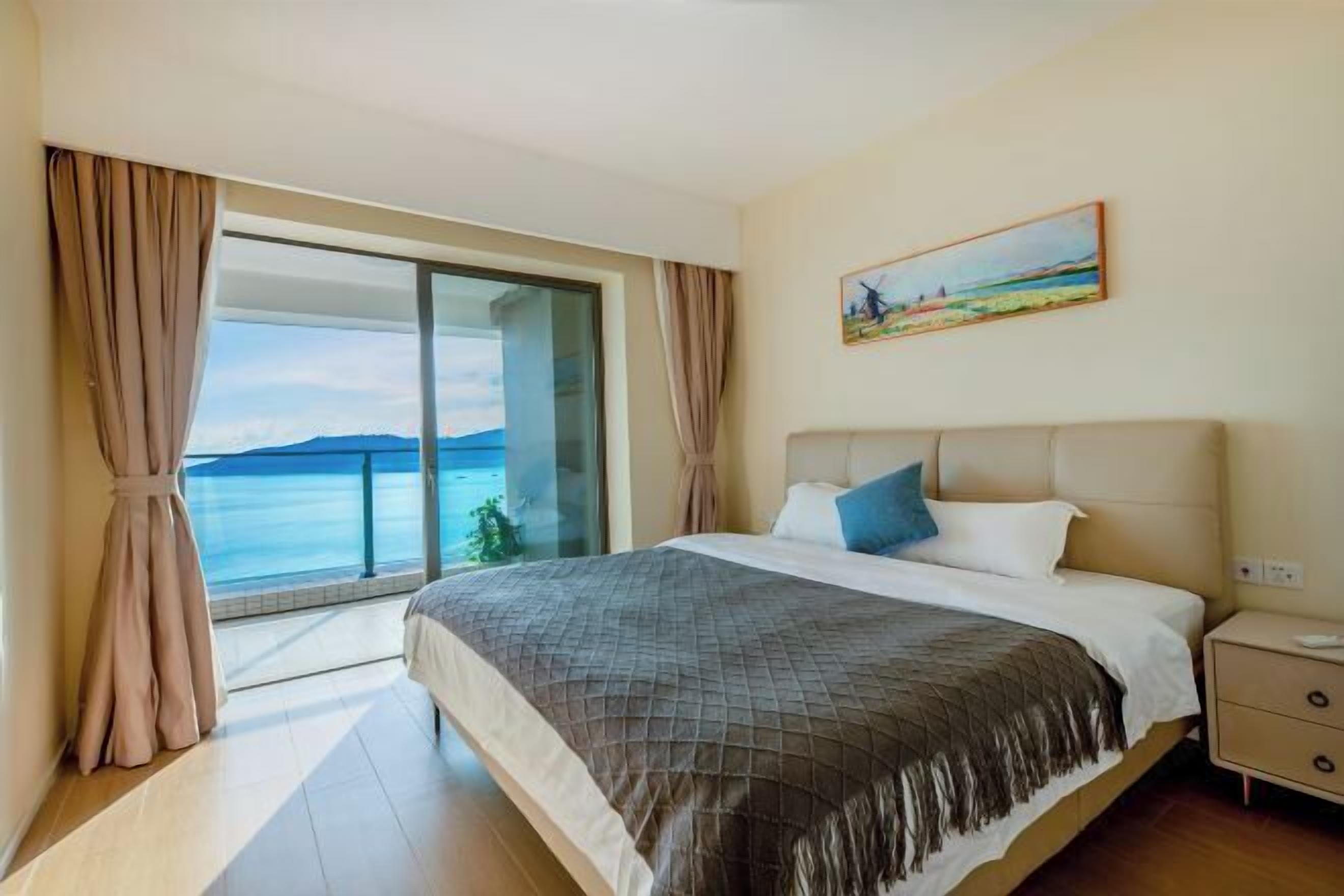 Un dormitorio con cama, mesita de noche, un cuadro y vistas al mar.