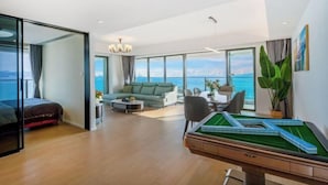 A modern living room with a pool table, a sofa, and a view of the sea.