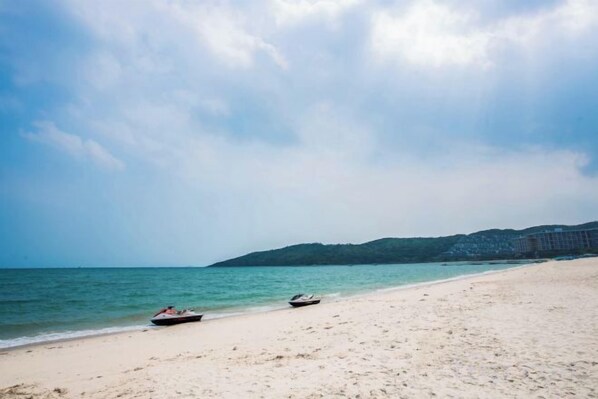 A beach with two boats on the sand and a distant hill.
