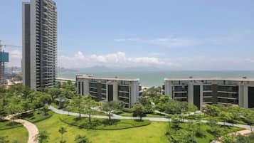 A high-rise building with a view of the sea and a landscaped area with pathways.