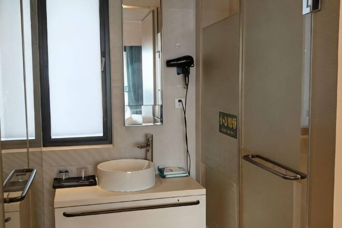 A bathroom with a sink, mirror, hairdryer, and a door with a handle.