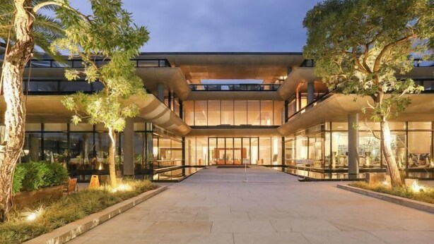 A modern building with a central courtyard, large glass windows, and a symmetrical design.