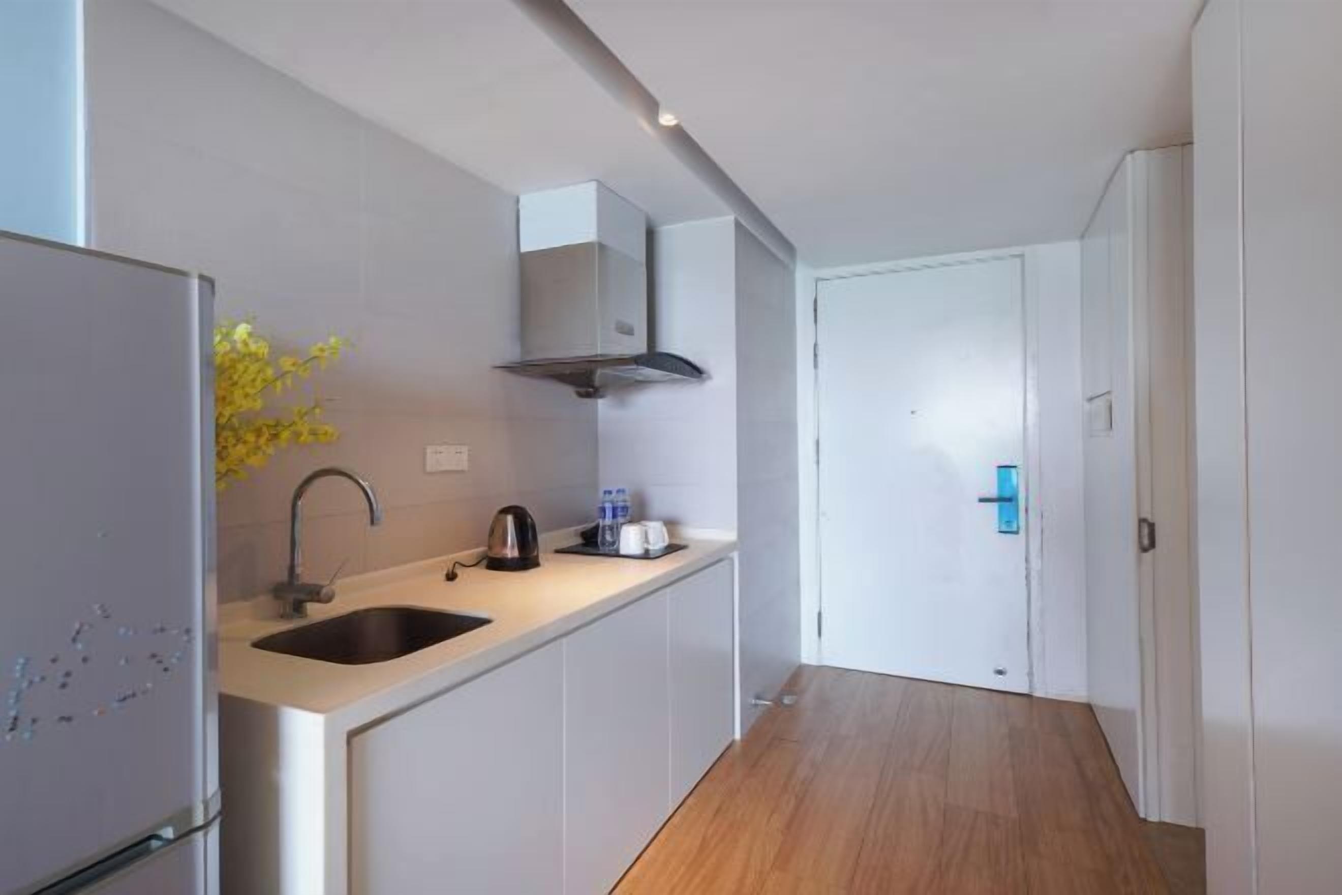 Una cocina moderna con un lavamanos empotrado, una campana extractora de acero inoxidable y piso de madera.