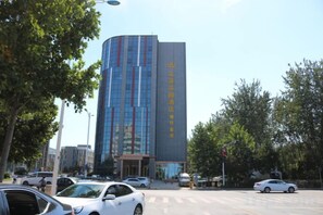 Un edificio moderno con fachada curva, varios pisos y una entrada despejada.