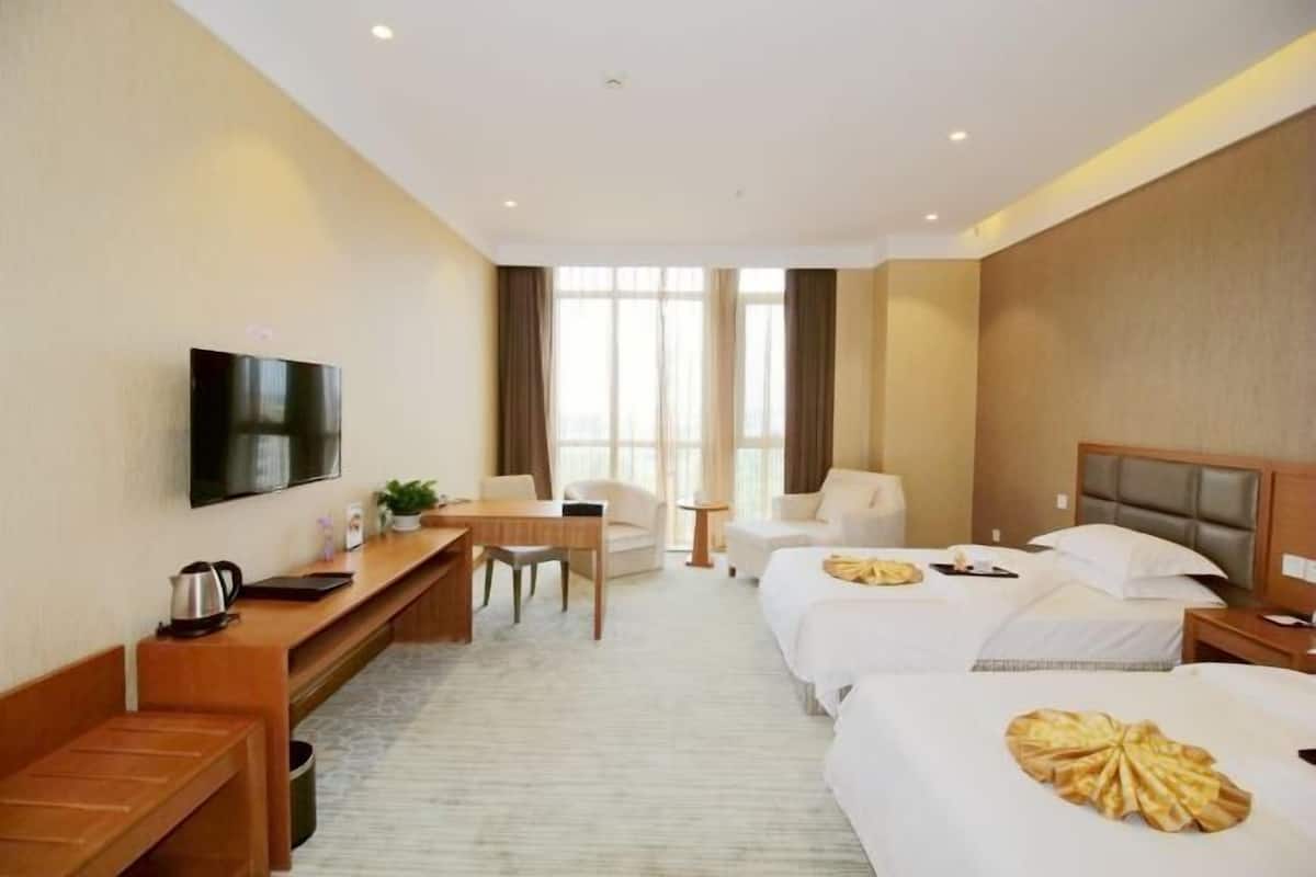 Une chambre d’hôtel équipée d’une télévision, d’un bureau, de deux lits, d’un canapé et d’une grande fenêtre.