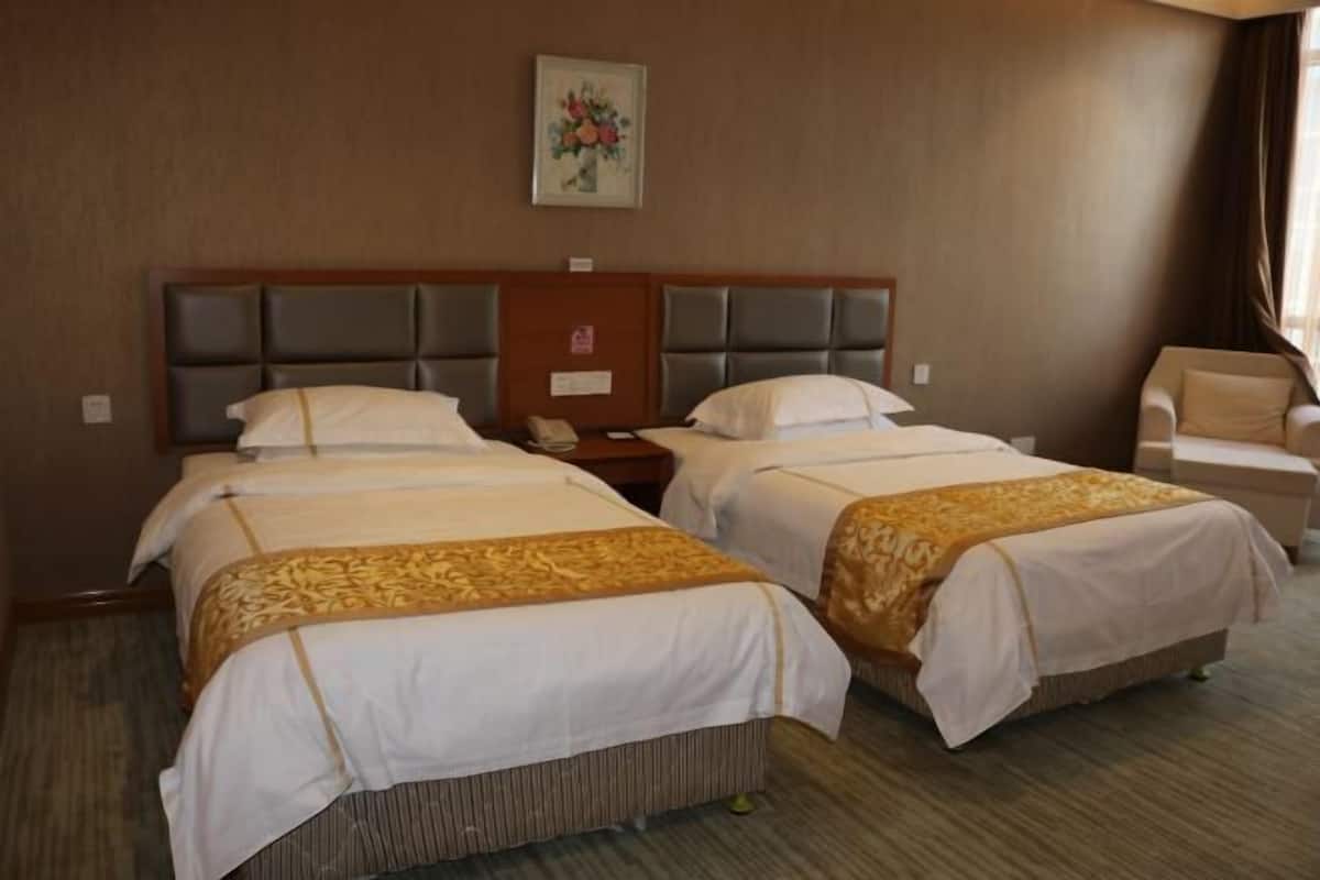 Une chambre d’hôtel avec deux lits, une table de chevet, une chaise et un tableau encadré au mur.