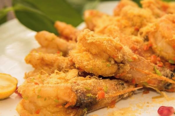 Un plato de comida rebozada y frita, posiblemente pollo o pescado, con una guarnición de hierbas y especias.