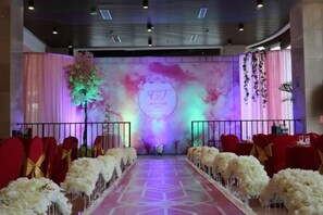 A stage with a backdrop and floral arrangements, a long aisle with chairs, and a railing. - Huaxi Garden Hotel (Qingdao Liuting Airport) (Qingdao)