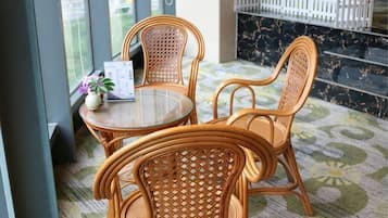 Wicker furniture with a glass table, a potted plant, and a menu on the table.