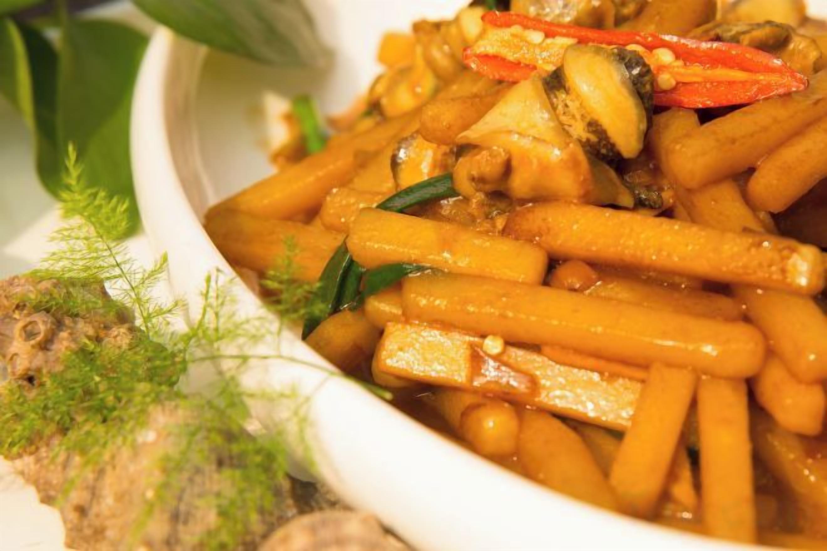 Un tazón de vegetales salteados con tofu y garbanzos, adornado con hierbas.