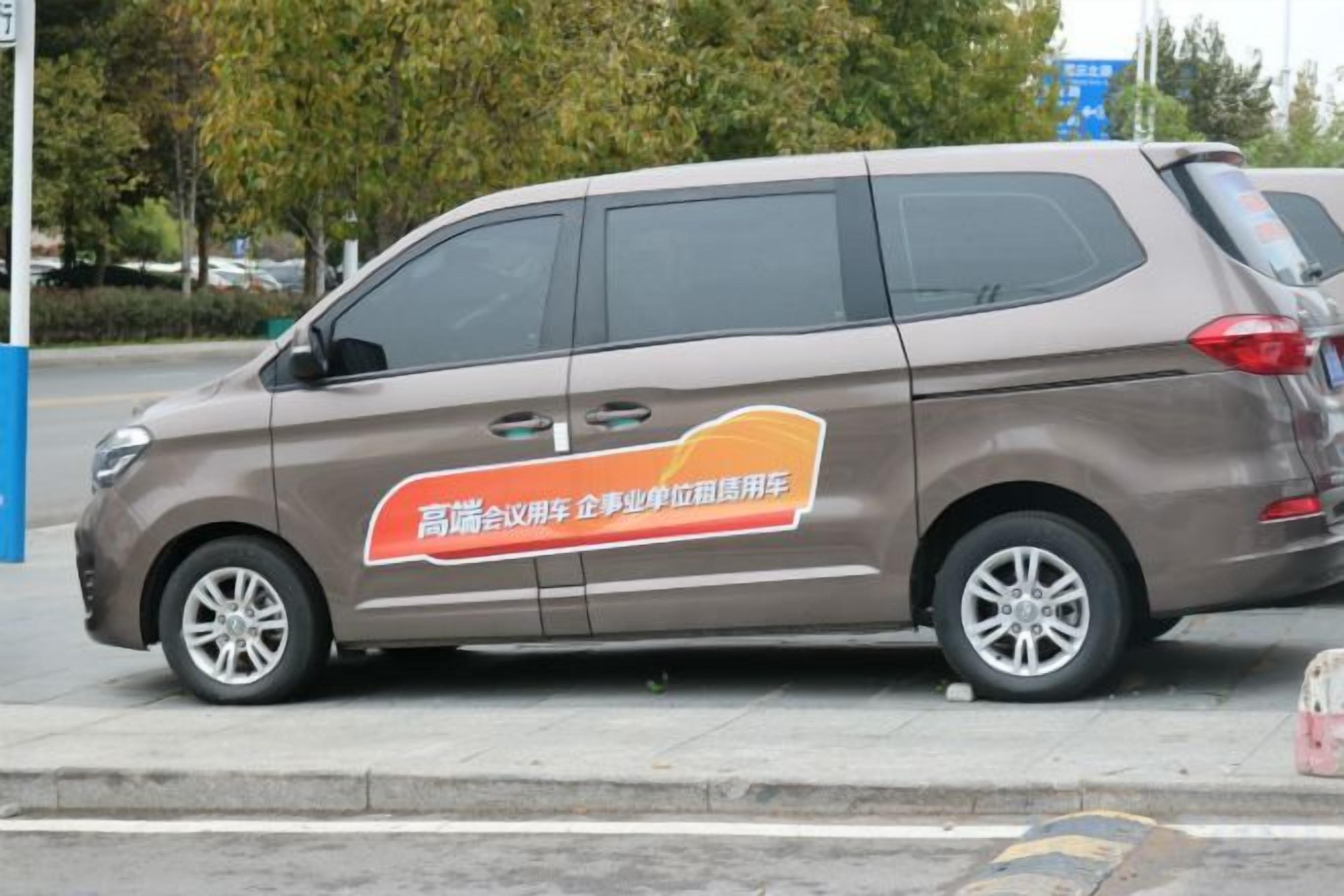A brown minivan parked on the side of a road.