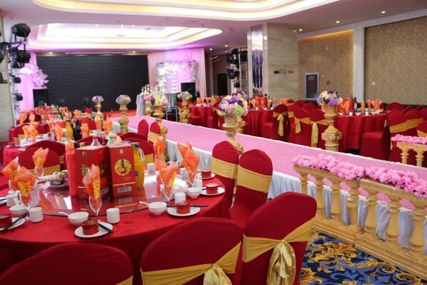 A banquet hall with round tables set for a formal event, featuring red and gold tablecloths and floral centerpieces. - Huaxi Garden Hotel (Qingdao Liuting Airport) (Qingdao)