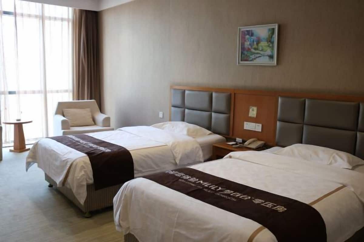 Une chambre d’hôtel avec deux lits, une chaise, une table de chevet et un tableau au mur.
