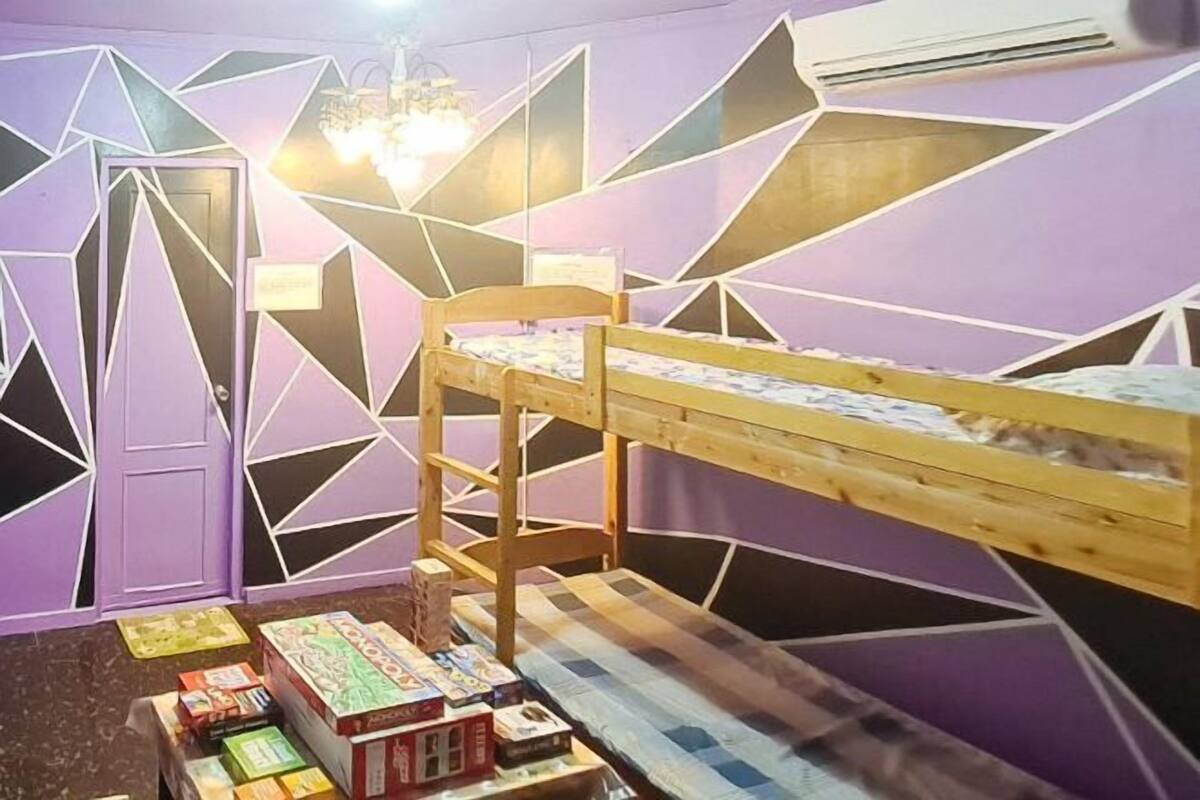 A room with a bunk bed, geometric wall design, and a chandelier.