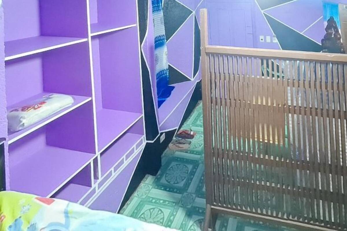 A room with purple shelving units, a wooden crib, and a patterned floor.