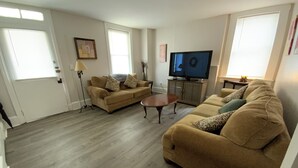 Ein Wohnzimmer mit zwei Sofas, einem Couchtisch, einem Fernseher und einer Lampe.