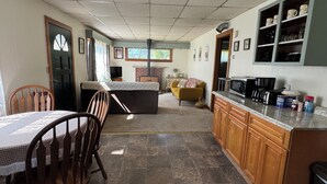 A spacious kitchen with a dining area, a fireplace, and a living room with a sofa. - Charming 2-bedroom house in Tiona with sunset views and everything you need. (Tiona)