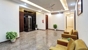 A modern lobby with a marble floor, a ceiling fan, and a reception desk with a plant. - Hotel Golden Era (Noida)